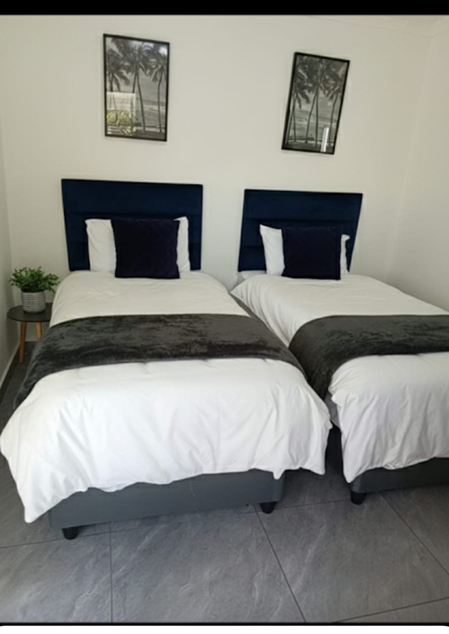 Deluxe twin room guesthouse Bellville South - premium navy blue headboards with quality bedding and palm artwork